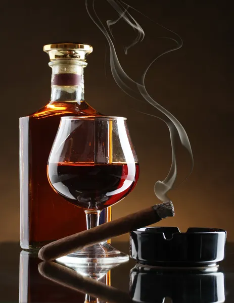 Palack és a pohár pálinkát és szivart a barna háttér — Stock Fotó