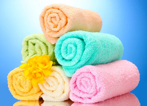 Barevné ručníky a květiny na modrém pozadí — Stock fotografie