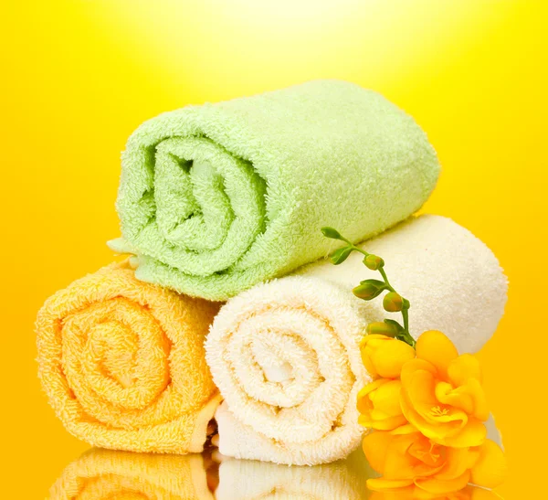 Asciugamani colorati e fiori su sfondo giallo — Foto Stock