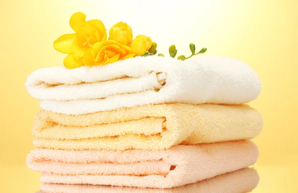 Bunte Handtücher und Blumen auf gelbem Hintergrund — Stockfoto