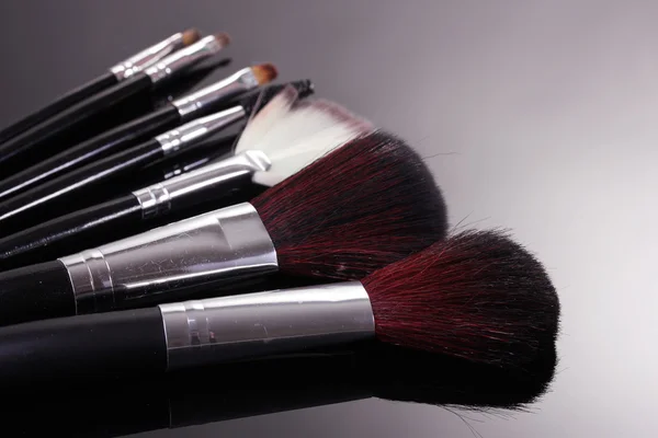 Make-up borstels op grijze achtergrond — Stockfoto