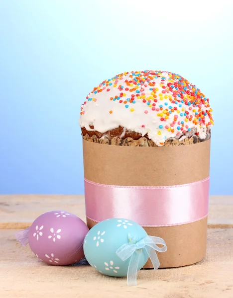 Krásné velikonoční dort se vejce na dřevěný stůl na modrém pozadí — Stock fotografie