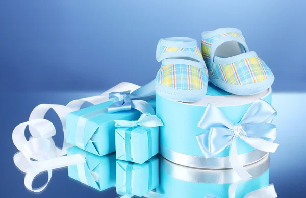 Piękne prezenty i trzewiki dziecka na niebieskim tle — Zdjęcie stockowe