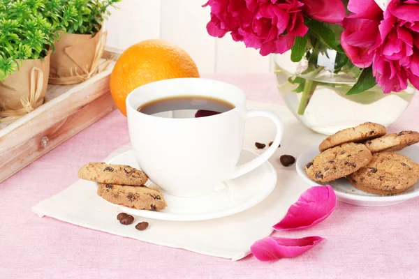 Xícara de café, biscoitos, laranja e flores na mesa no café — Fotografia de Stock