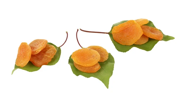 Вкусные сушеные абрикосы на зеленых листьях, изолированных на белых — стоковое фото