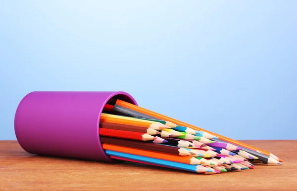 Crayons de couleur en verre sur table en bois sur fond bleu — Photo