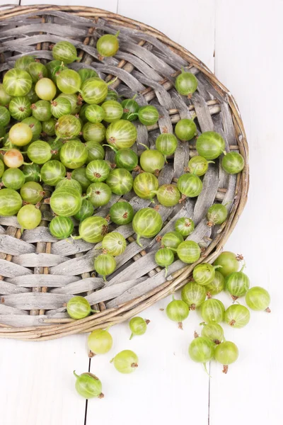 Green gooseberry on wicker mat on wooden background — Stock Photo, Image