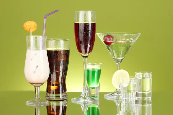 Olika alkoholhaltiga drycker på grön bakgrund — Stockfoto