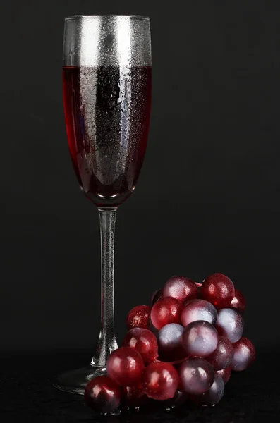 Um copo de vinho e uvas isolado no fundo preto close-up — Fotografia de Stock
