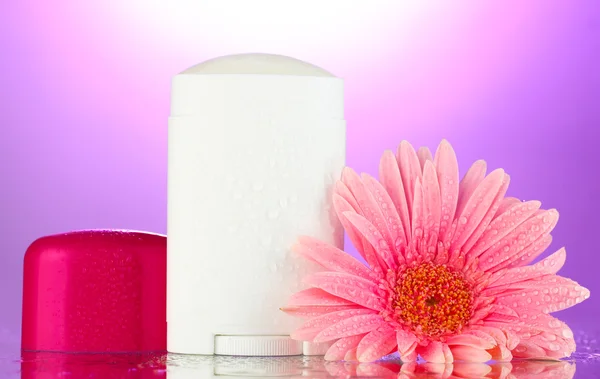 Deodorant with flower on purple background — Stock Photo, Image