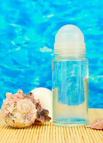 Desodorizante e conchas no fundo do mar azul — Fotografia de Stock