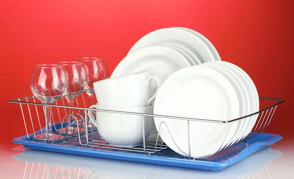 Pratos limpos em stand no fundo vermelho — Fotografia de Stock