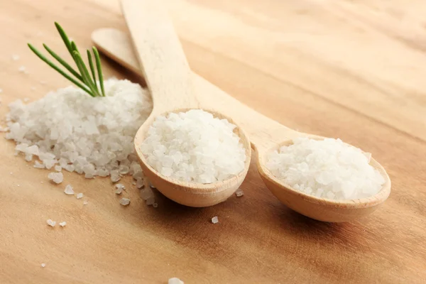 Salz in Löffeln mit frischem Rosmarin auf Holzgrund — Stockfoto