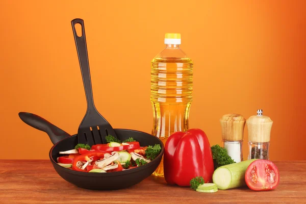 Frying pan with vegetables on red background — Stock Photo, Image