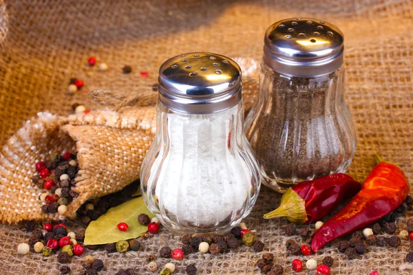 Molinos de sal y pimienta y especias sobre fondo de arpillera —  Fotos de Stock