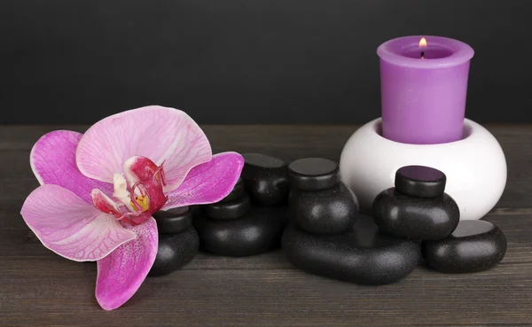 Piedras de spa con flor de orquídea y vela sobre mesa de madera sobre fondo gris — Foto de Stock