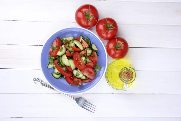 Свежий салат с помидорами и огурцами на белом деревянном фоне — стоковое фото