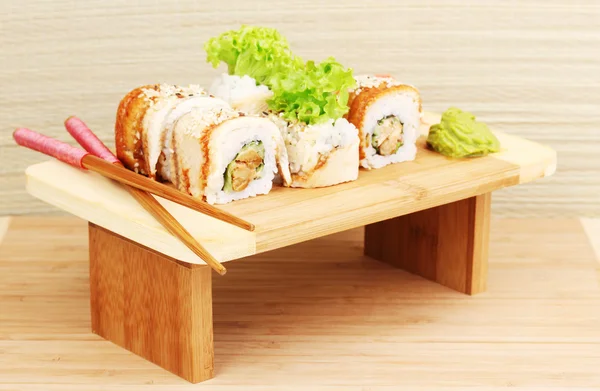 Tasty rolls served on wooden plate on wooden background — Stock Photo, Image