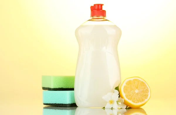 食器洗い液体スポンジと背景黄色の花とレモン添え — ストック写真
