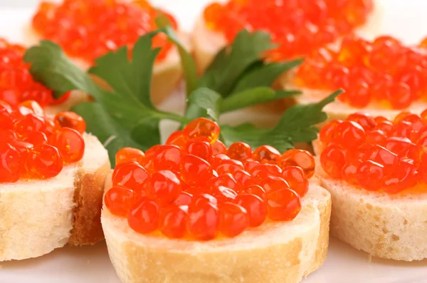 Roter Kaviar auf Brot auf weißem Teller in Großaufnahme — Stockfoto