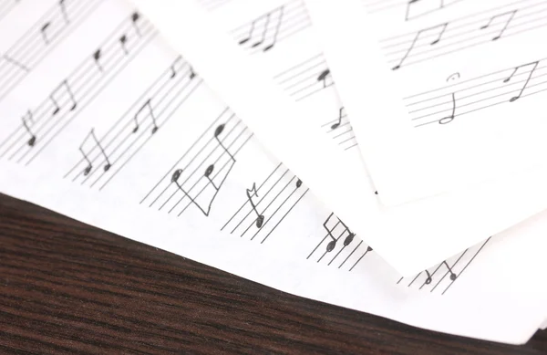 Notas musicales y plumas sobre mesa de madera — Foto de Stock