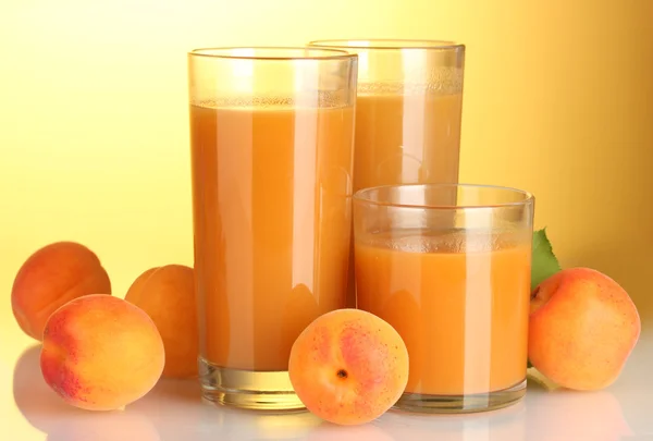 Gläser Aprikosensaft auf gelbem Hintergrund — Stockfoto