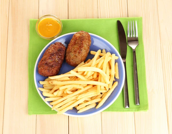 Batatas fritas com hambúrgueres no prato em fundo de madeira close-up — Fotografia de Stock
