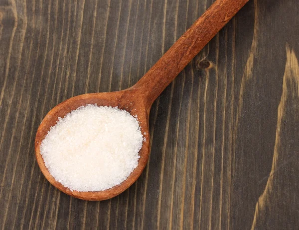 White sugar in spoon on wooden background — Stock Photo, Image
