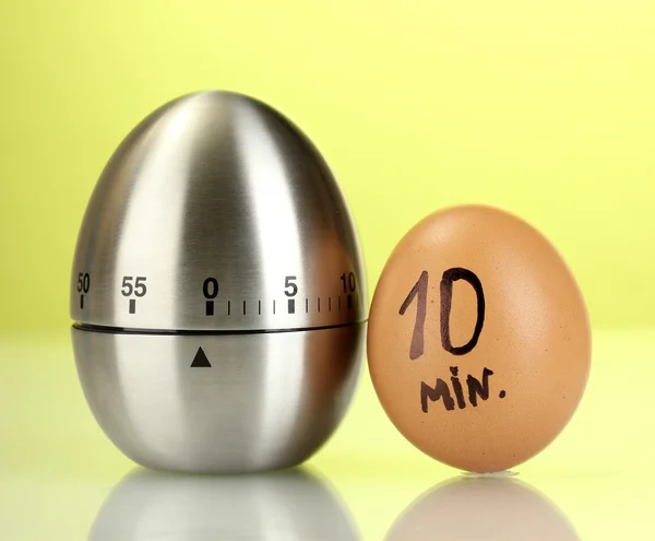 Egg timer and egg on green background — Stock Photo, Image