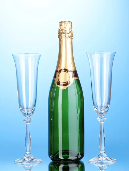 Fles champagne en bekers op blauwe achtergrond — Stockfoto