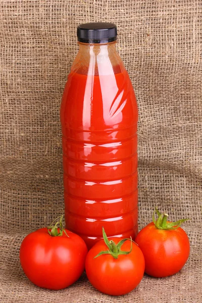 Tomatensap in fles op rouwgewaad achtergrond — Stockfoto