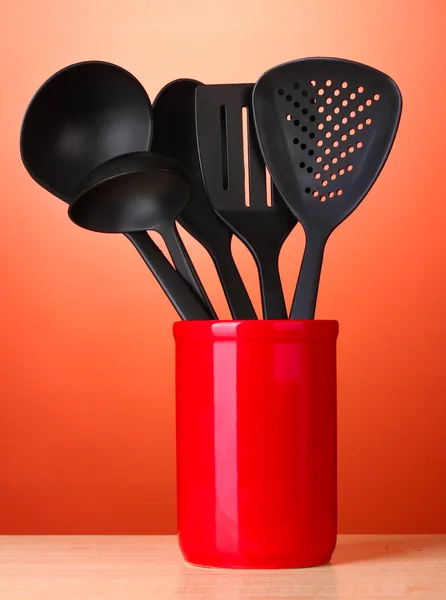 Zwarte keukengerei in cup op rode bakground — Stockfoto