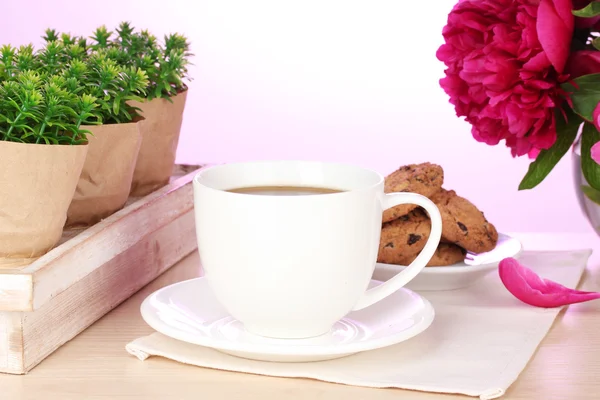 Kopp kaffe, kakor och blommor på bord i café — Stockfoto