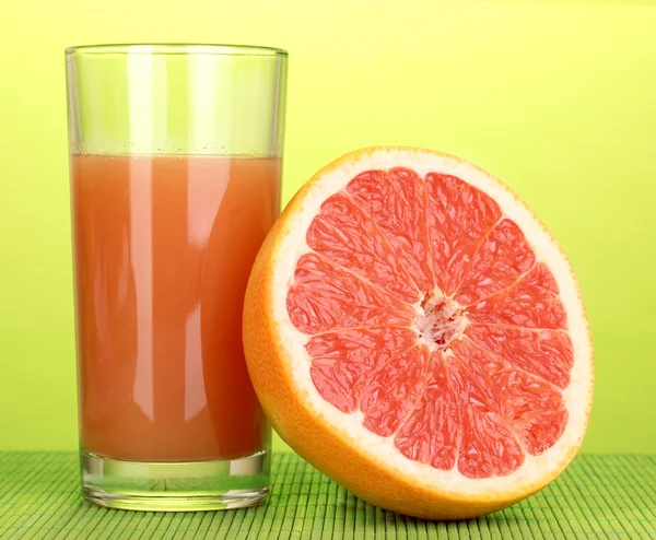 Grapefruitsaft und Grapefruit auf Bambusmatte auf grünem Hintergrund — Stockfoto