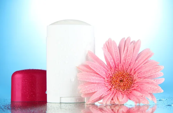 Desodorante con flor sobre fondo azul — Foto de Stock