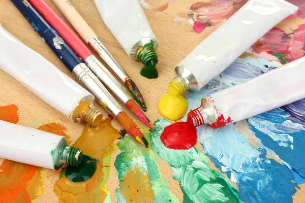 Soyut akrilik boya, boya tüpleri ve fırçalar ahşap palet üzerinde — Stok fotoğraf