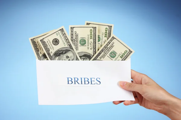 stock image Woman's hand holding an envelope with money on blue background