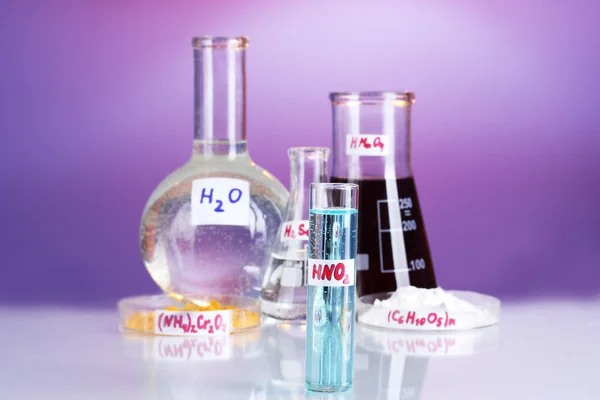Probówki z różnych kwasów i środków chemicznych na fioletowym tle — Zdjęcie stockowe