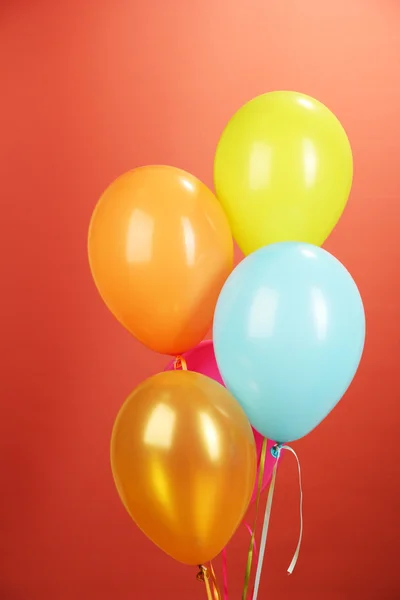 Färgglada ballonger på röd bakgrund — Stockfoto