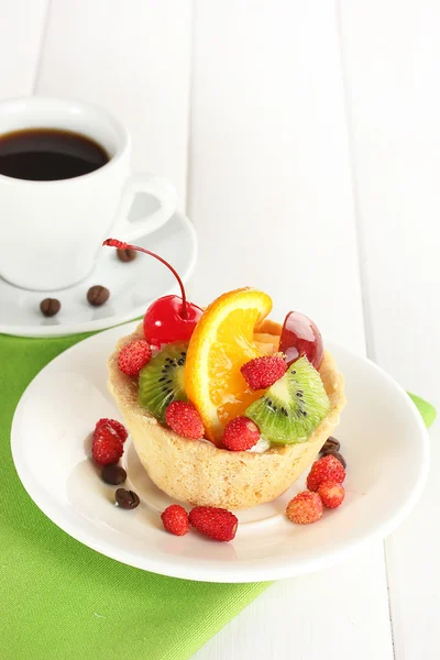 Torta dolce con frutta sul piatto e tazza di caffè sul tavolo di legno — Foto Stock