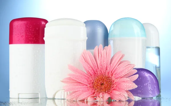 Deodorant botttles met bloem op blauwe achtergrond — Stockfoto
