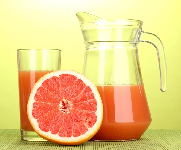 Grapefruit juice and grapefruit on bamboo mat on green background — Stock Photo, Image