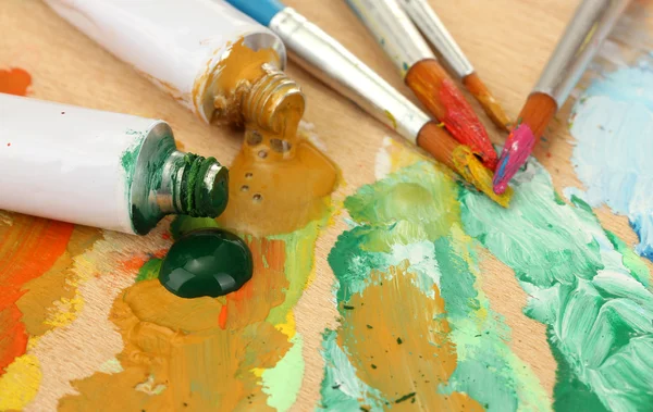 Abstrakte Acrylfarbe, Farbtuben und Pinsel auf Holzpalette — Stockfoto