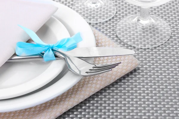 Placas brancas vazias, garfo e faca amarrados com uma fita e óculos em uma toalha de mesa cinza — Fotografia de Stock