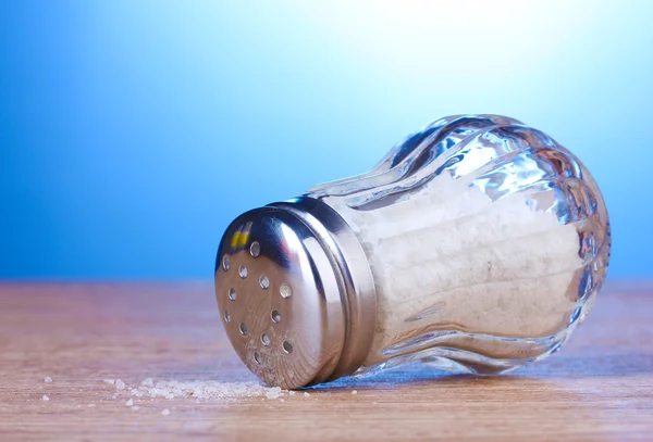 Glazen saltcellar met zout op houten tafel op blauwe achtergrond — Stockfoto