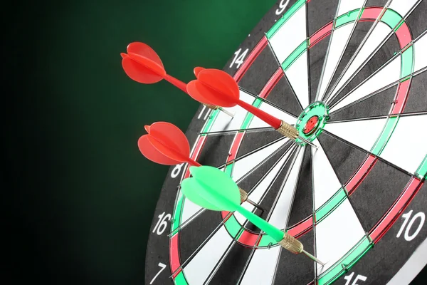 Dart board met darts op groene achtergrond — Stockfoto