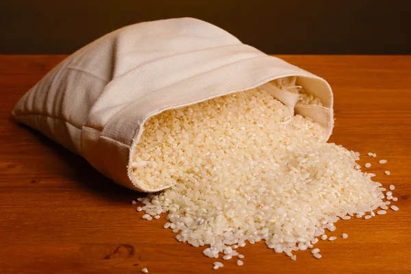 Tygpåse ris på träbord på brun bakgrund — Stockfoto