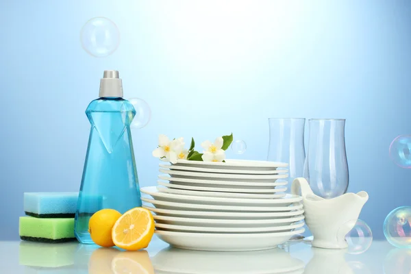 빈 깨끗 한 접시와 주방용 액체와 스폰지, 파란색 배경에 레몬 안경 — 스톡 사진