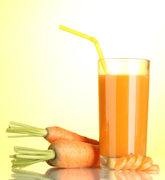 Vidro de suco de cenoura no fundo amarelo — Fotografia de Stock