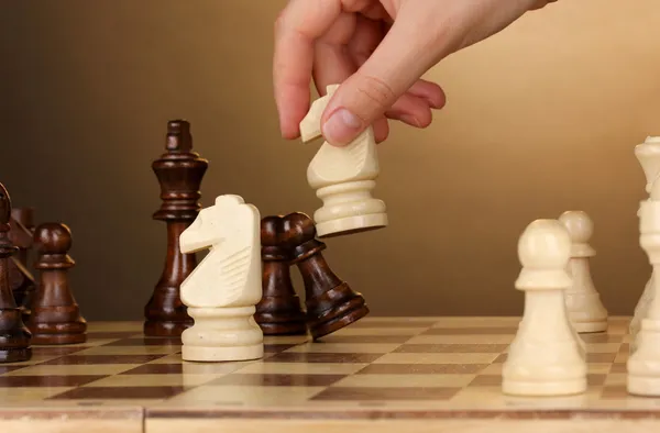 Šachovnice s šachové figurky na hnědé pozadí — Stock fotografie
